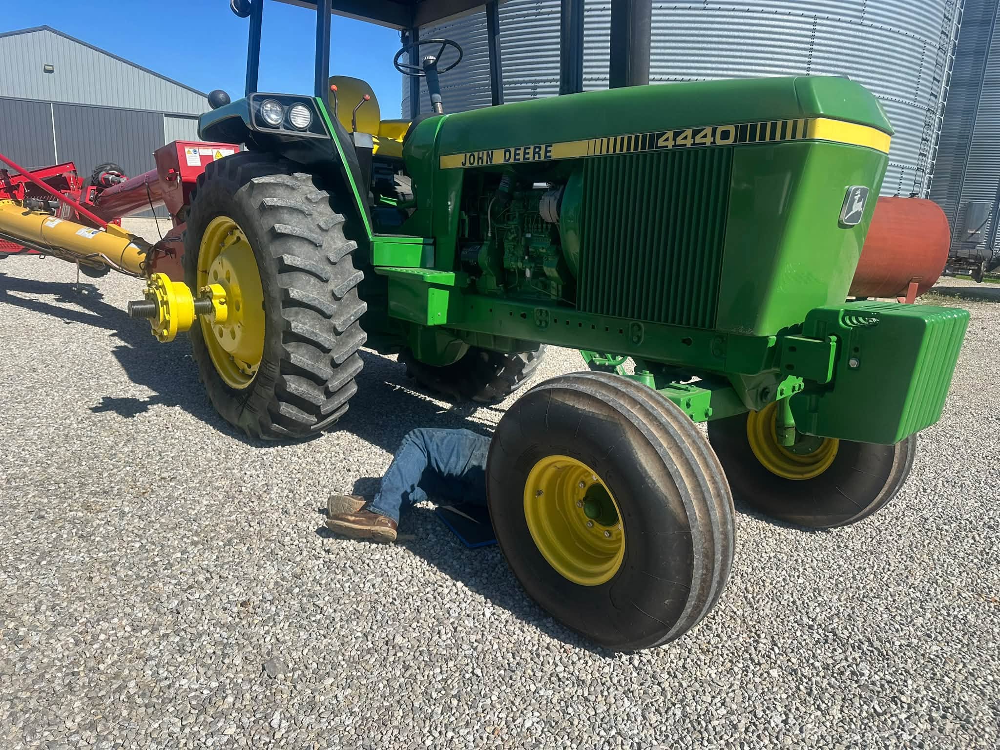 Paul working underneath a John Deere tractor